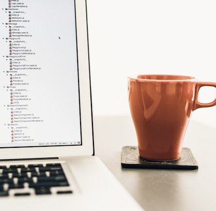 A laptop and a mug of coffee beside it.